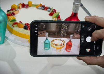 Cellulare che inquadra una torta e due bottiglie di lambrusco